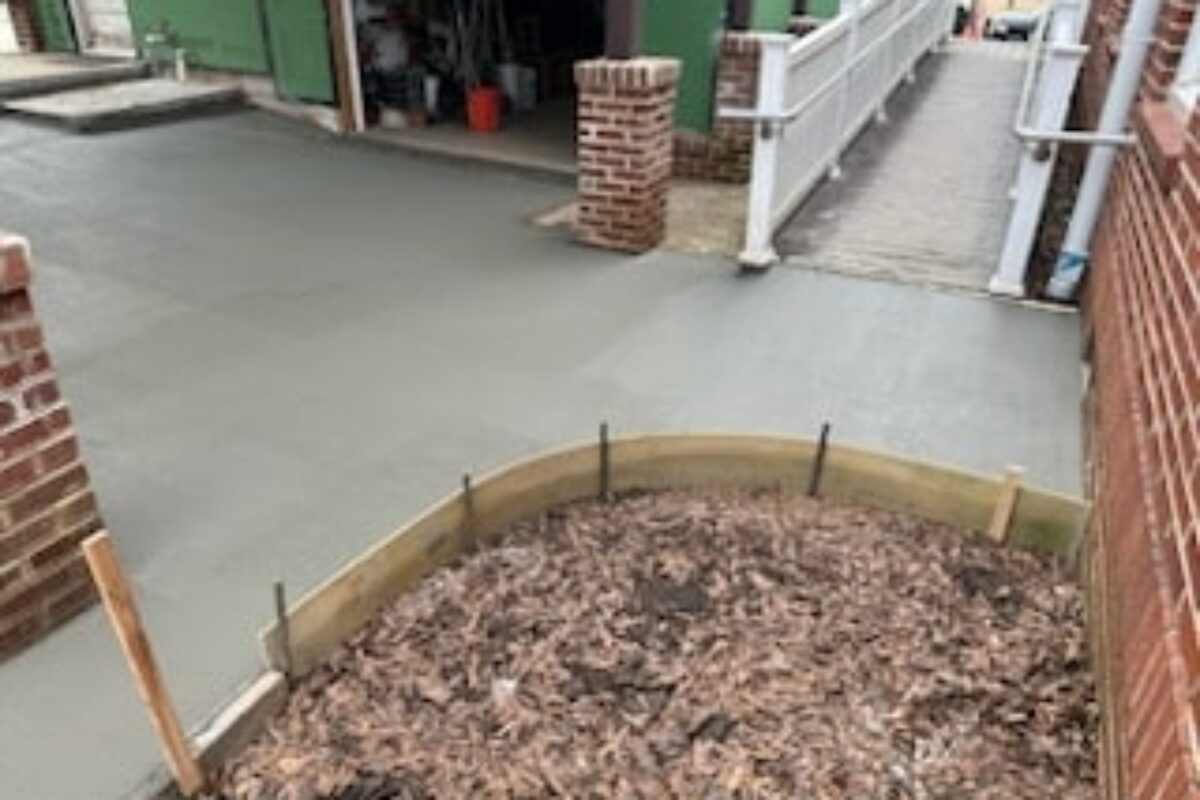 photo of freshly poured concrete around a brick building